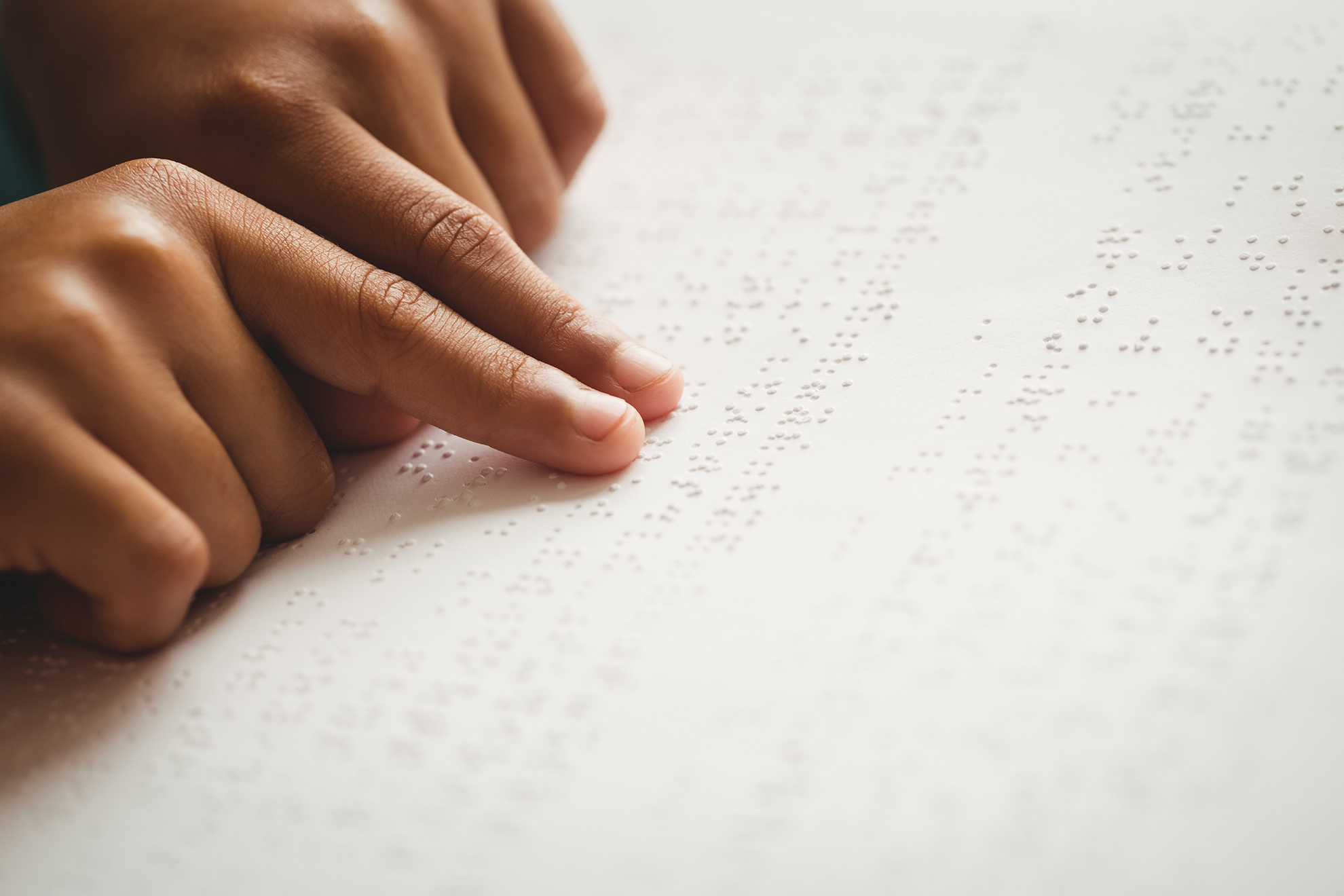 person's fingers reading braille document
