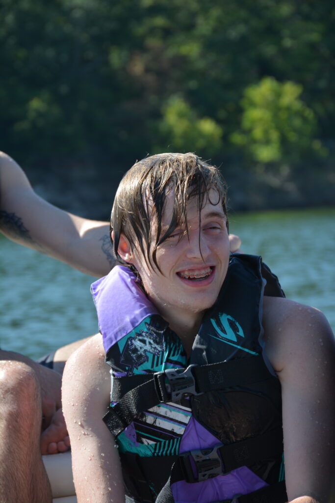 A camper smiles for the camera while dripping from his last dip in the lake.