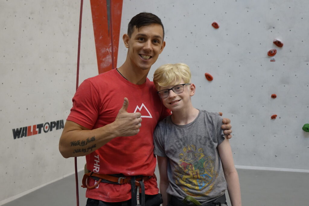 A camper poses with Para Olympic medalist Justin Salas during rock climbing day. 