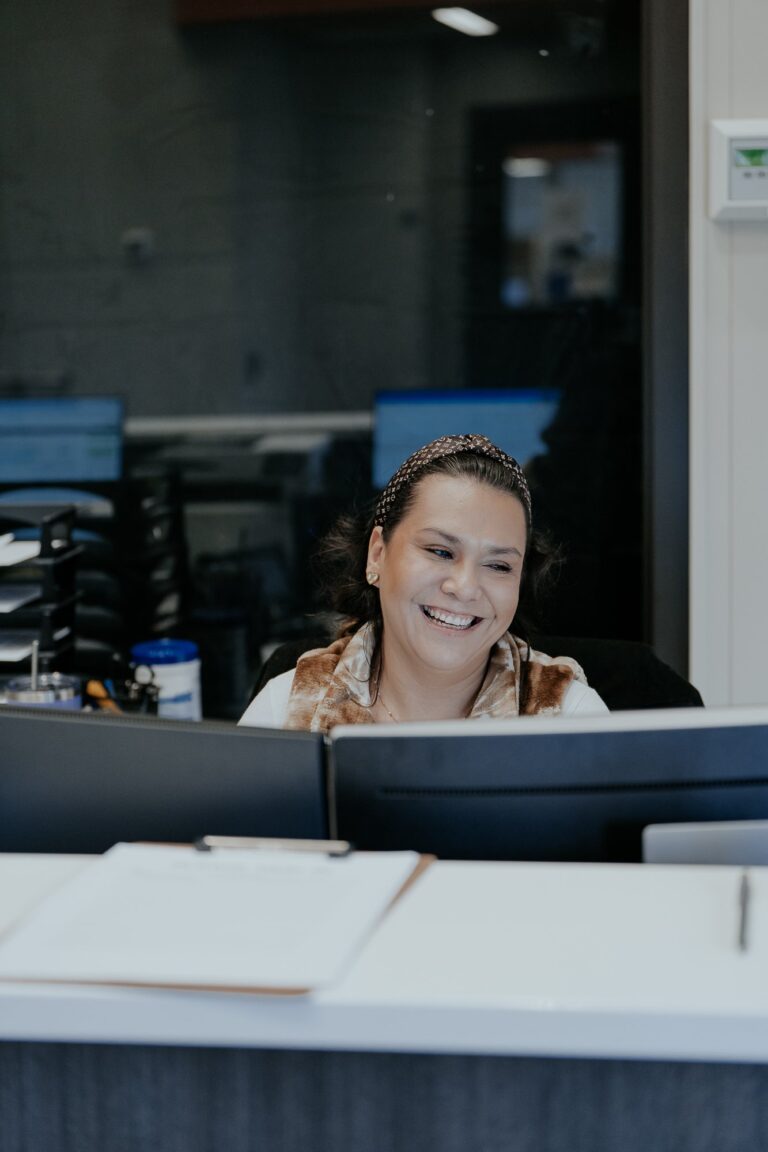 Melissa smiles big from behind the reception desk at NewView's clinic.