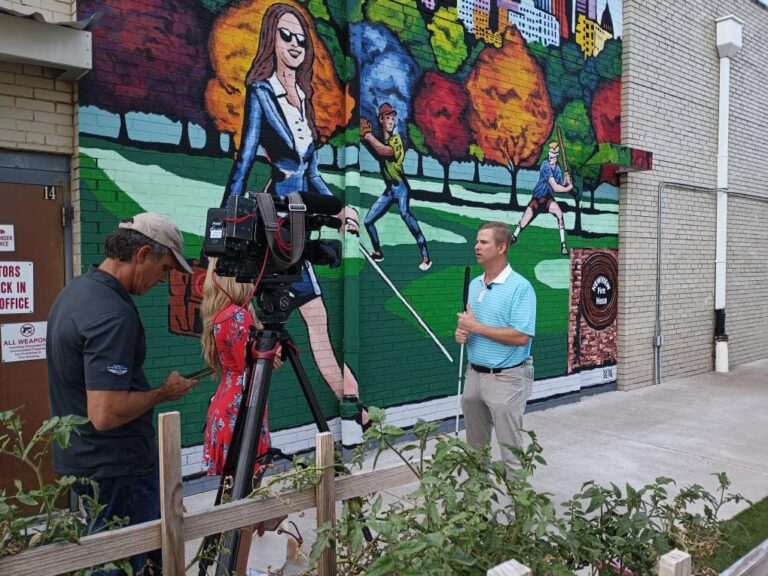 Mark Ivy offers an interview to a news station in front of John Bramblitt's mural