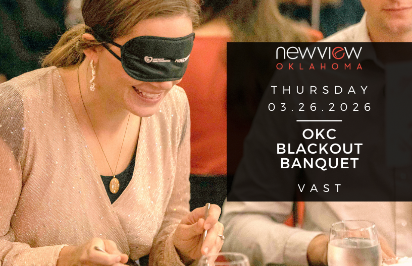 Woman who is blindfolded eats her delicious food at a NewView Blackout Banquet.