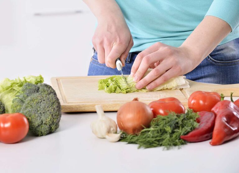 woman in kitchen slicing vegetables
