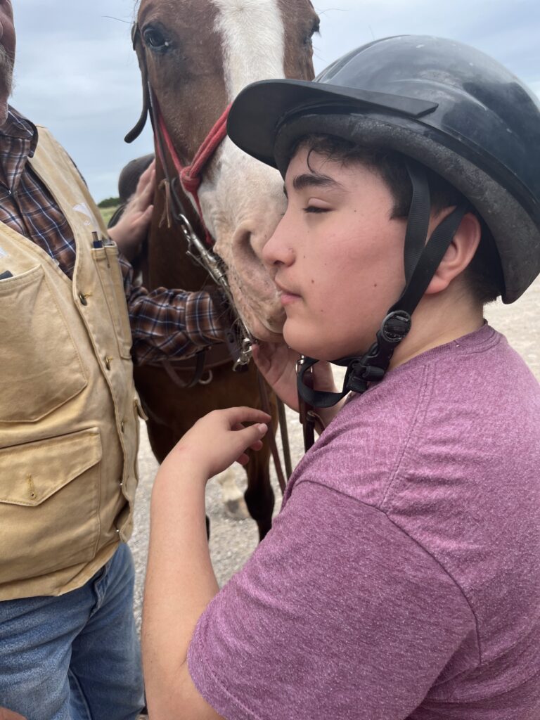 A camper putting his face to a horse's nose.