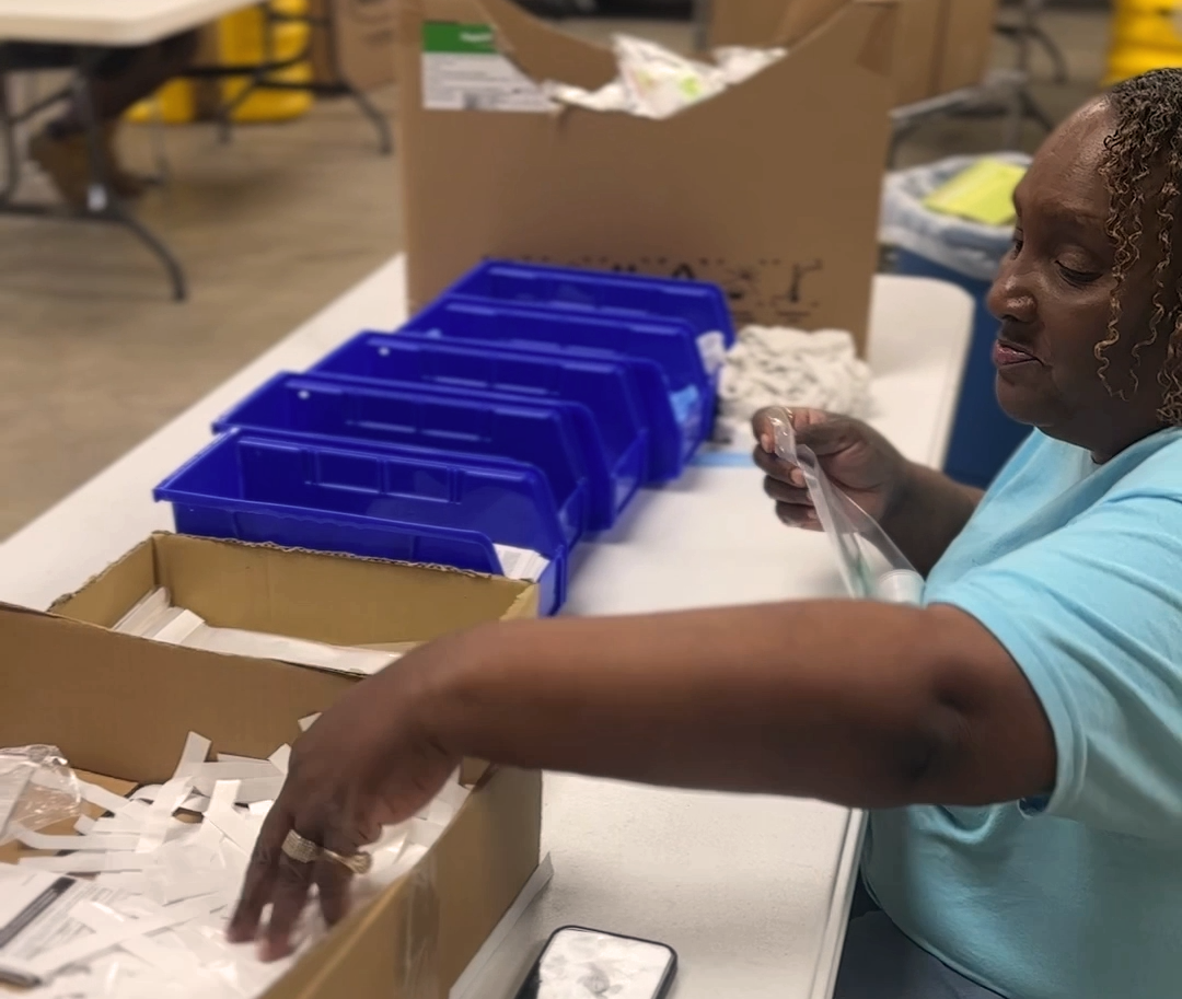 NVO employee putting together components for first aid kits.