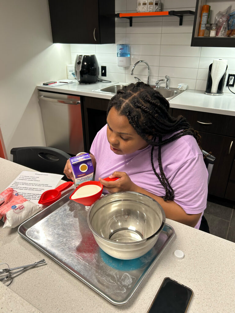 Keys to work attendee measuring out milk in the training kitchen.