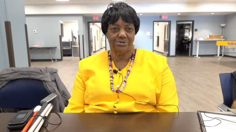 Diane Goodman sitting at a table in NewView's Community Room.