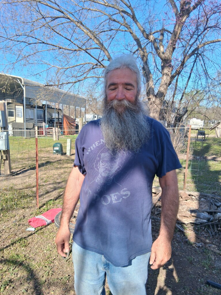 An image of Jason standing in his backyard on a beautiful blue-sky day. 