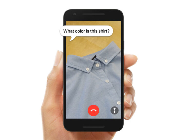 Picture of hand holding cell phone with photo of shirt and caption "What color is this shirt?"