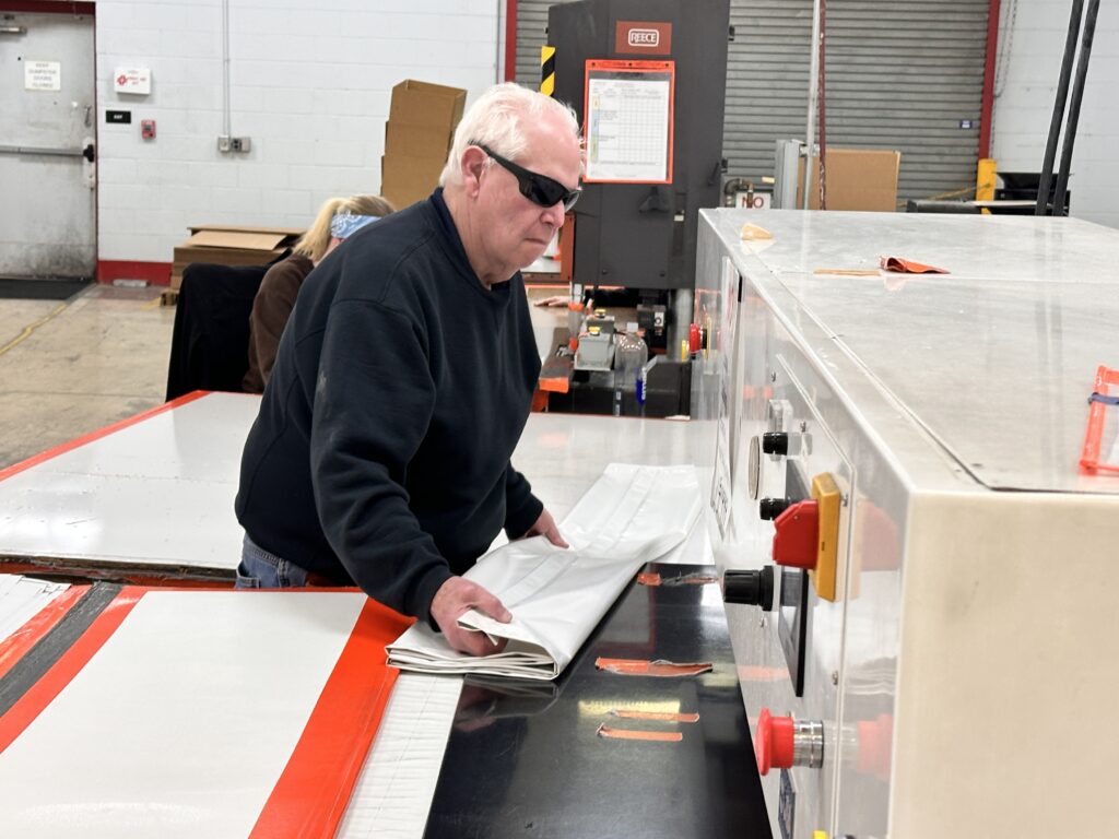 Man folding a vinyl shower curtain.