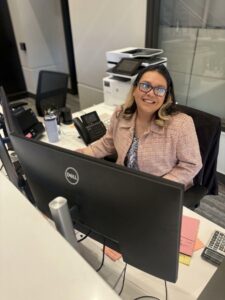 Melissa smiles while greeting clients as our receptionist.