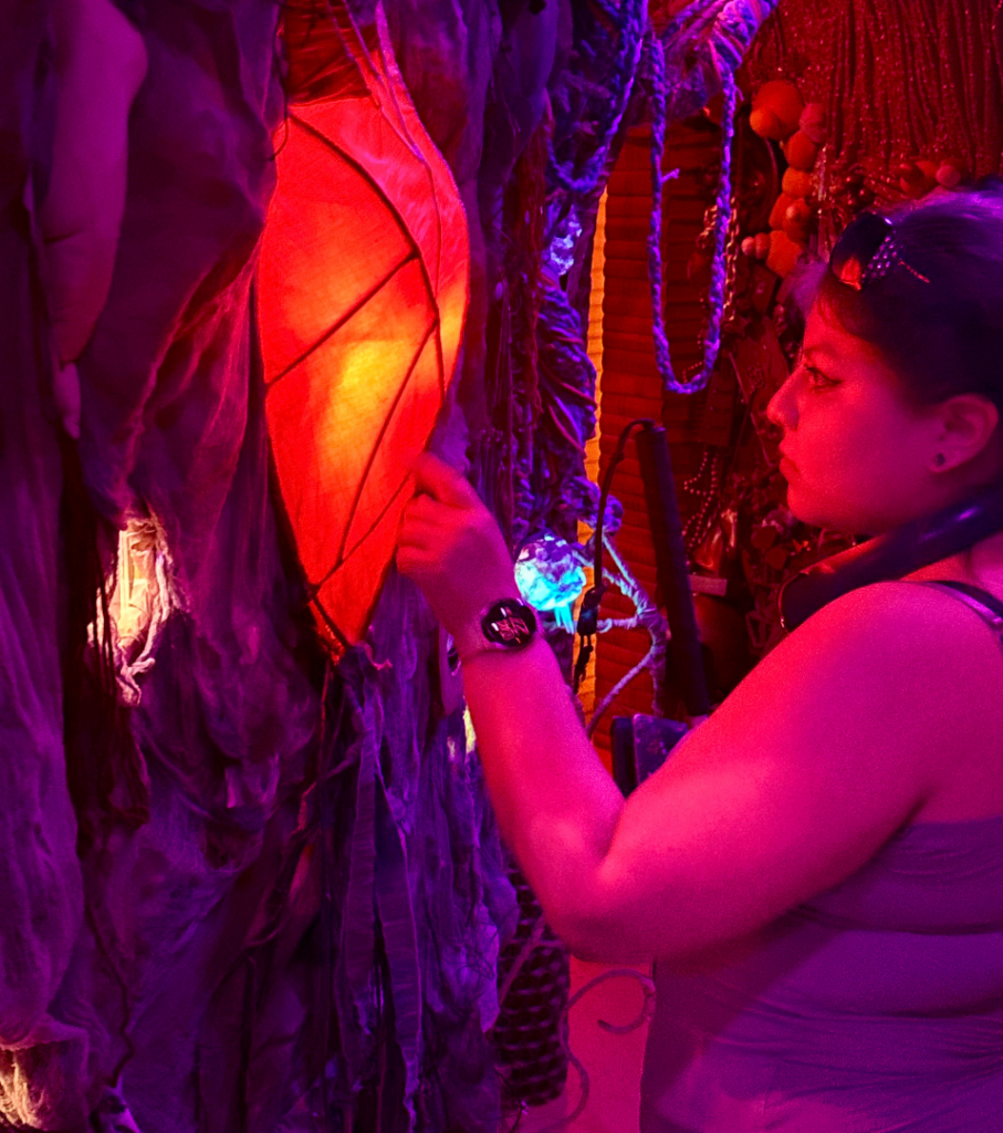 Serenity looking at a large glowing red light on the wall inside Factory Obscura