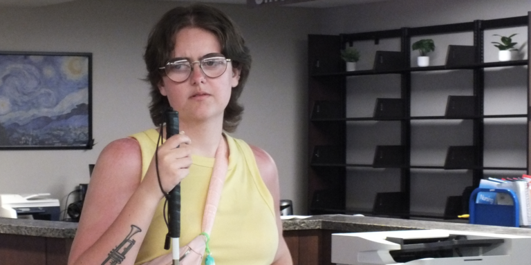 Alex inside the library at Rose State College during Keys to Work. She's holding her white cane.